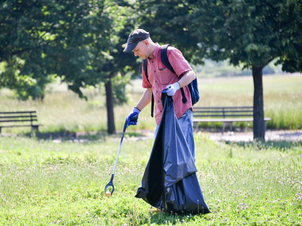 a person picks up trash from the lawn in a park